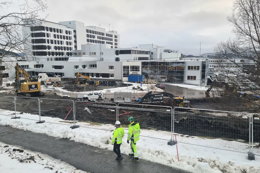 Noen menn i gule jakker som står i snøen