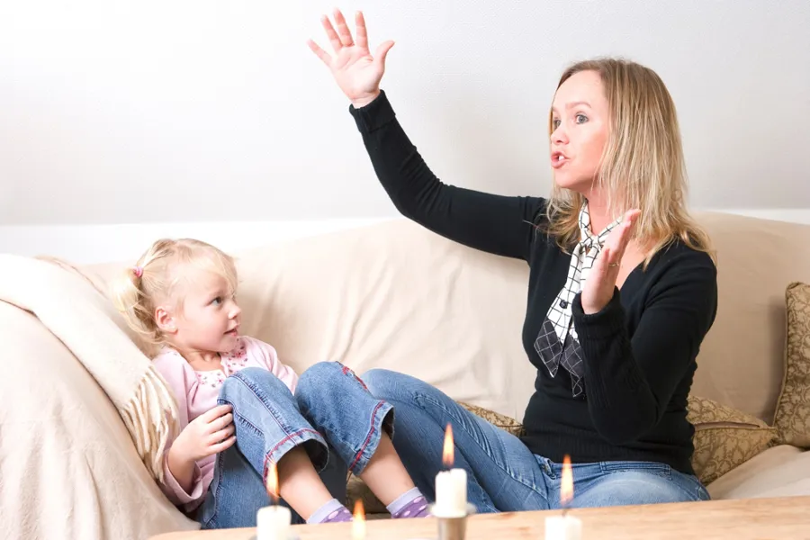 et barn og en kvinne som sitter i en sofa der kvinnen forteller noe