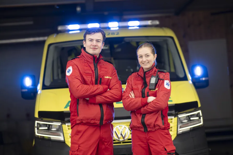 To ambulansearbeidarar står framfor ambulansebil