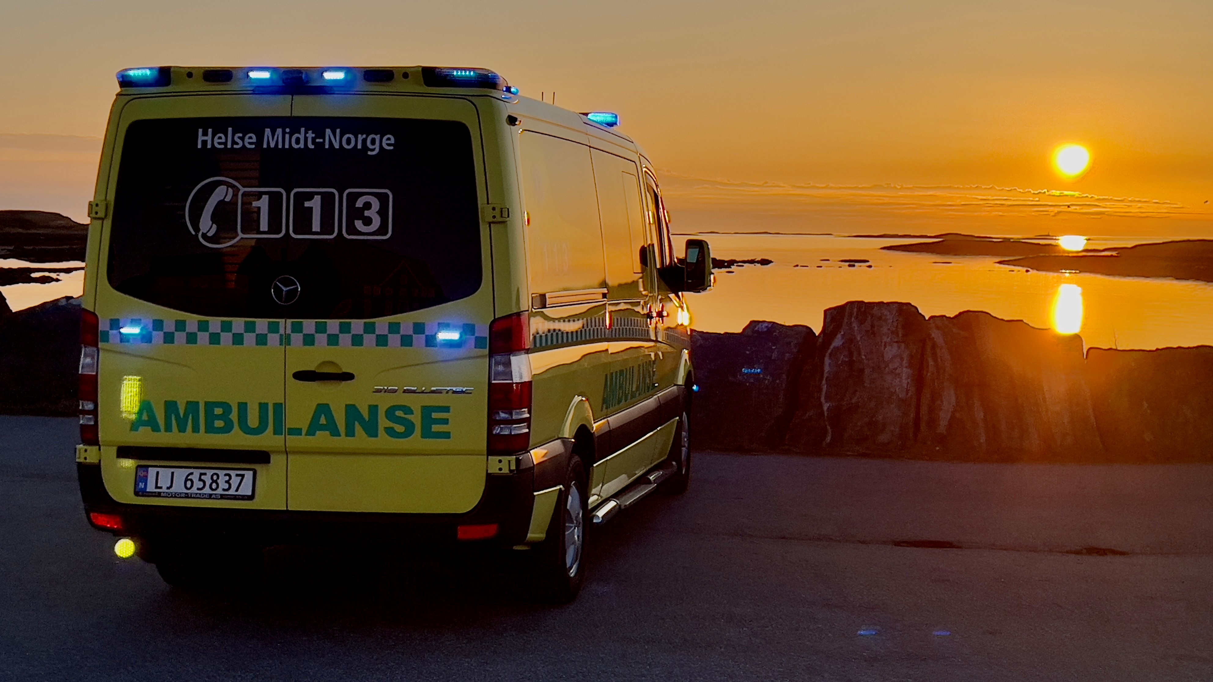 Ambulansebil som står parkert med solnedgang i bakgrunnen