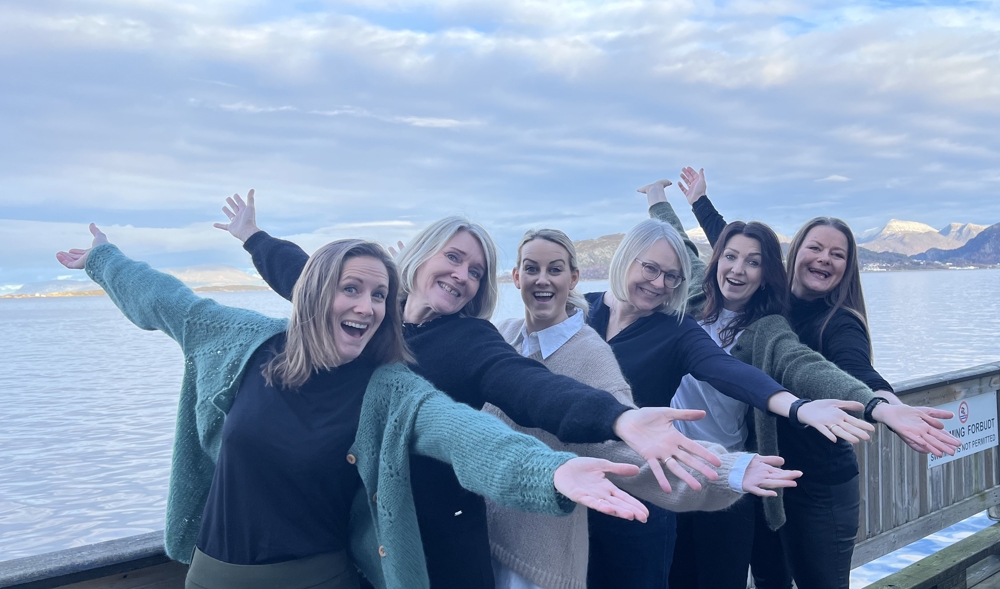 En gruppe kvinner som poserer for et bilde på en bro over vann