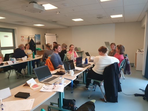 En gruppe mennesker som sitter ved skrivebord med bærbare datamaskiner