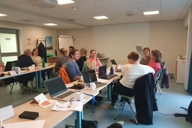 En gruppe mennesker som sitter ved skrivebord med bærbare datamaskiner