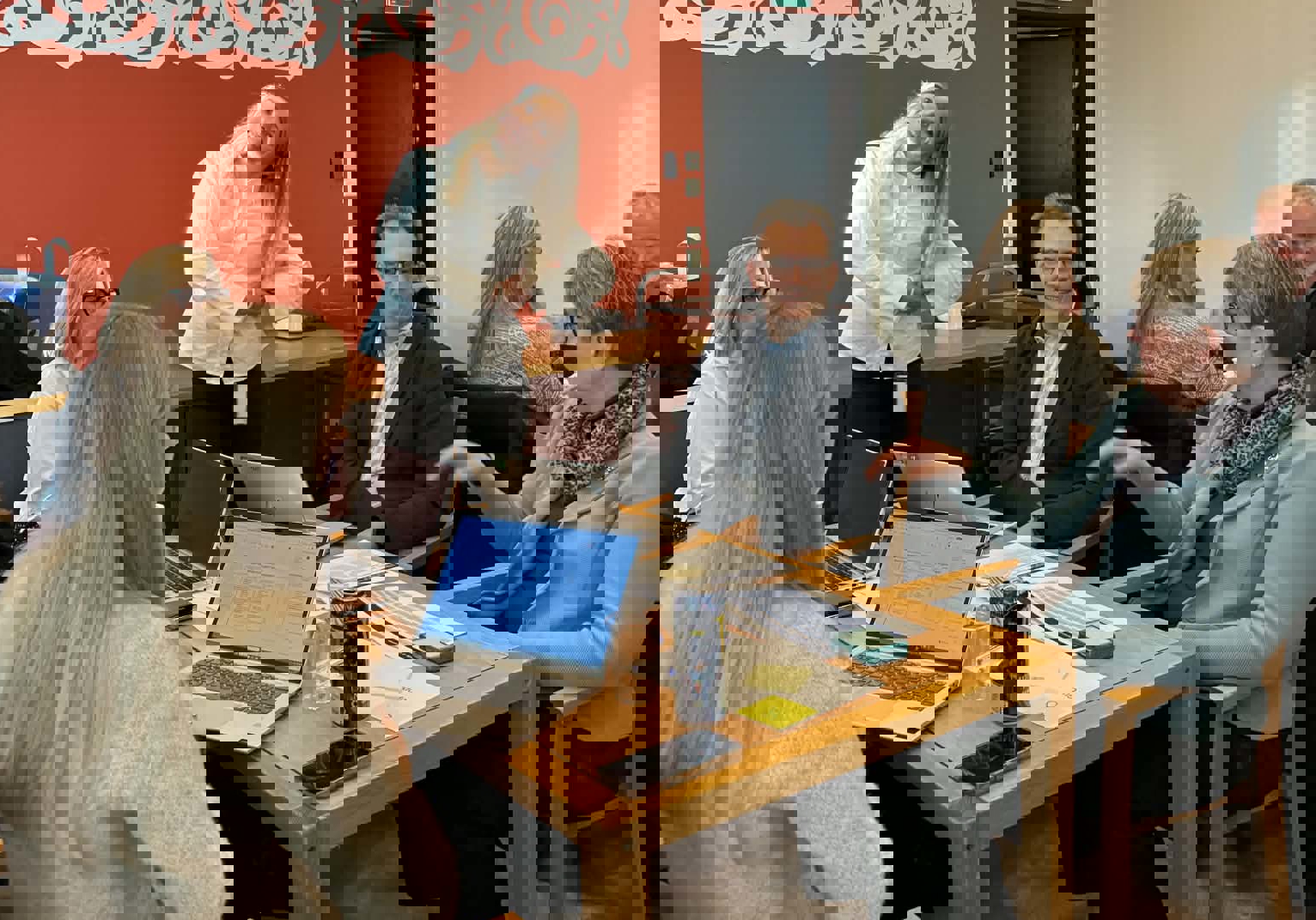 En gruppe mennesker som sitter rundt et bord med bærbare datamaskiner