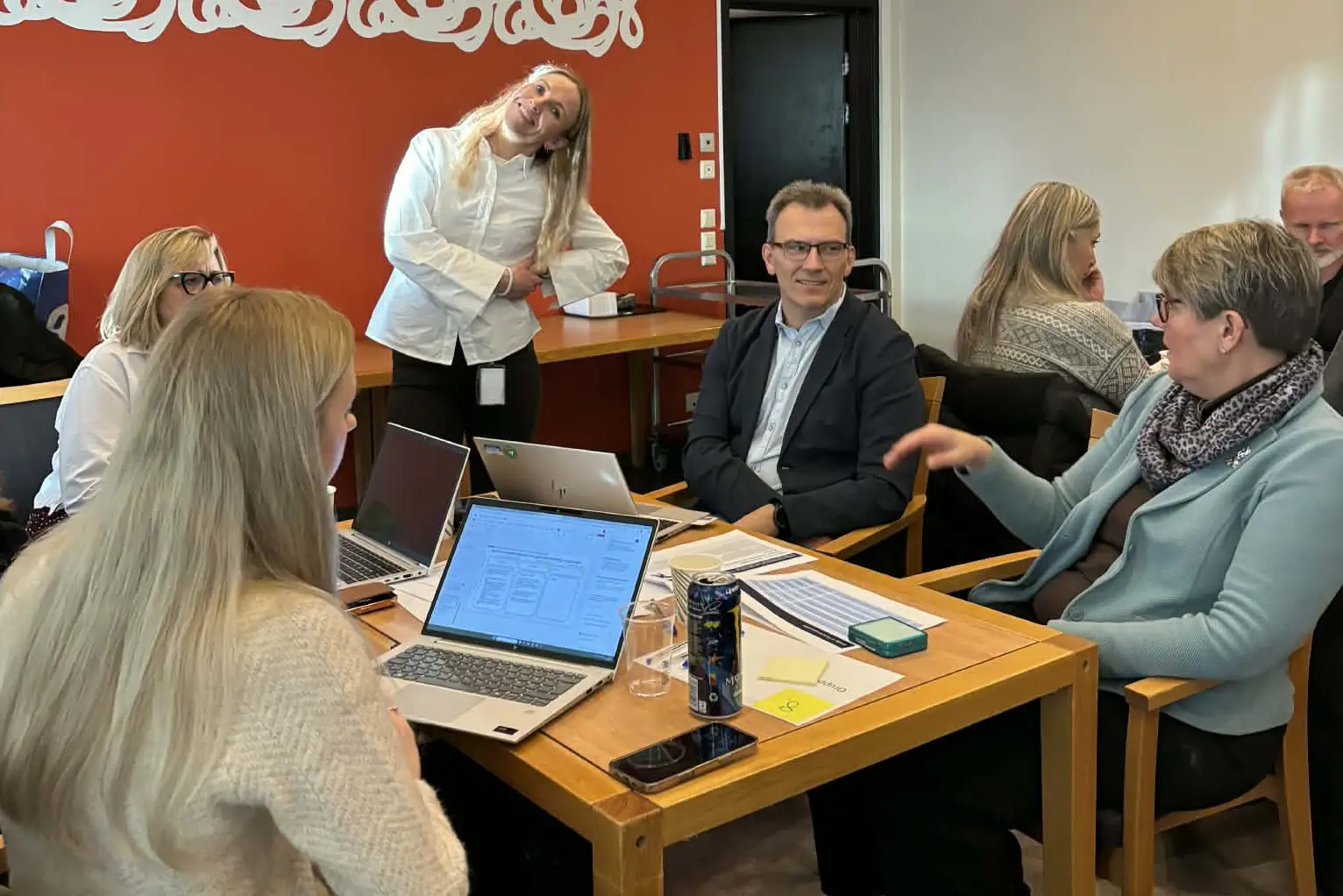 En gruppe mennesker som sitter rundt et bord med bærbare datamaskiner