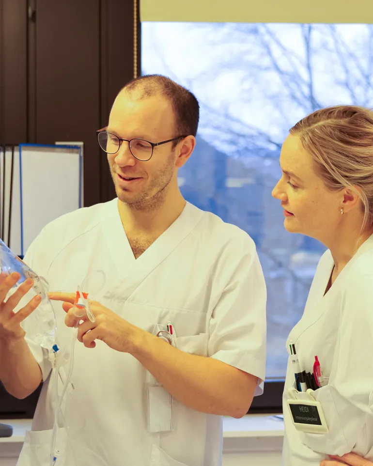 En lege som viser en pasient noe på datamaskinen