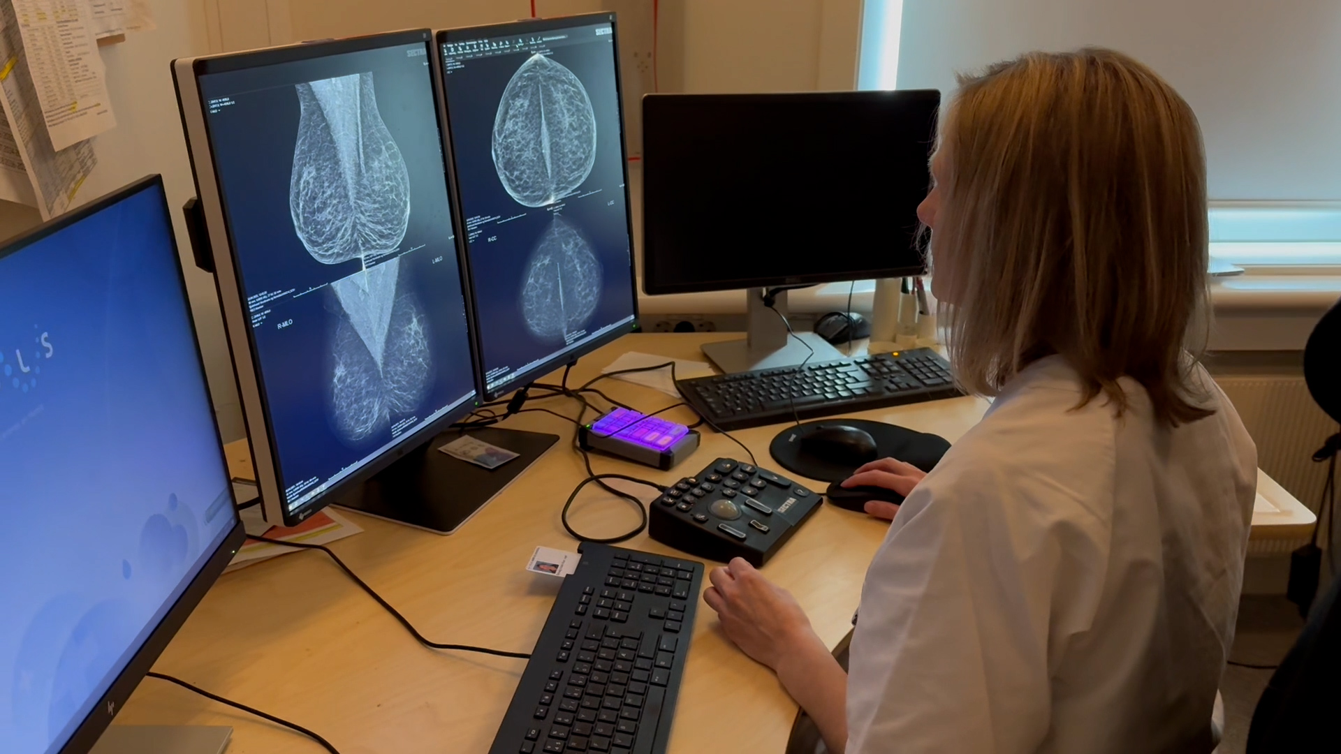 En person som sitter ved et skrivebord med flere skjermer