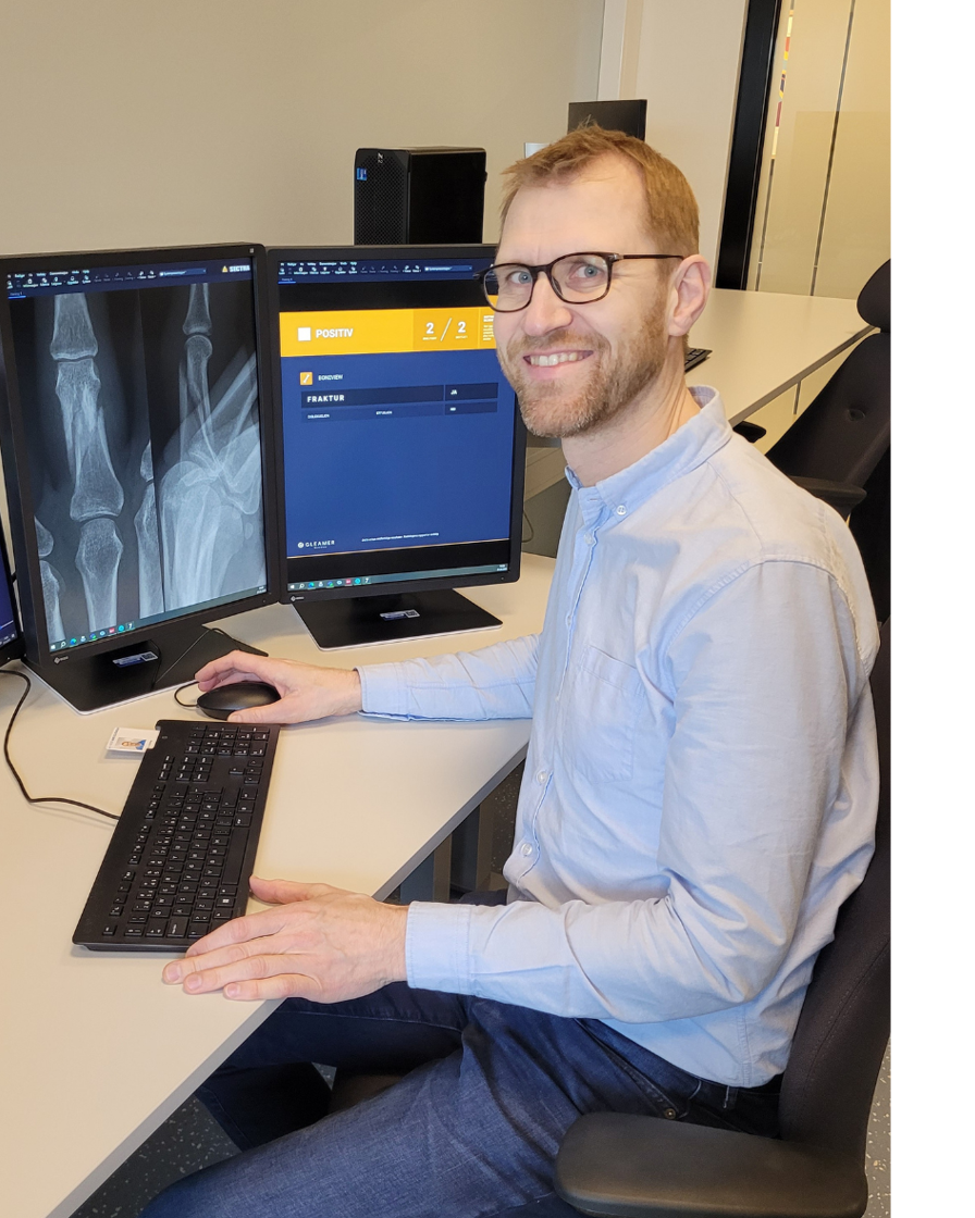 En mann som sitter ved et skrivebord med en datamaskin og et tastatur