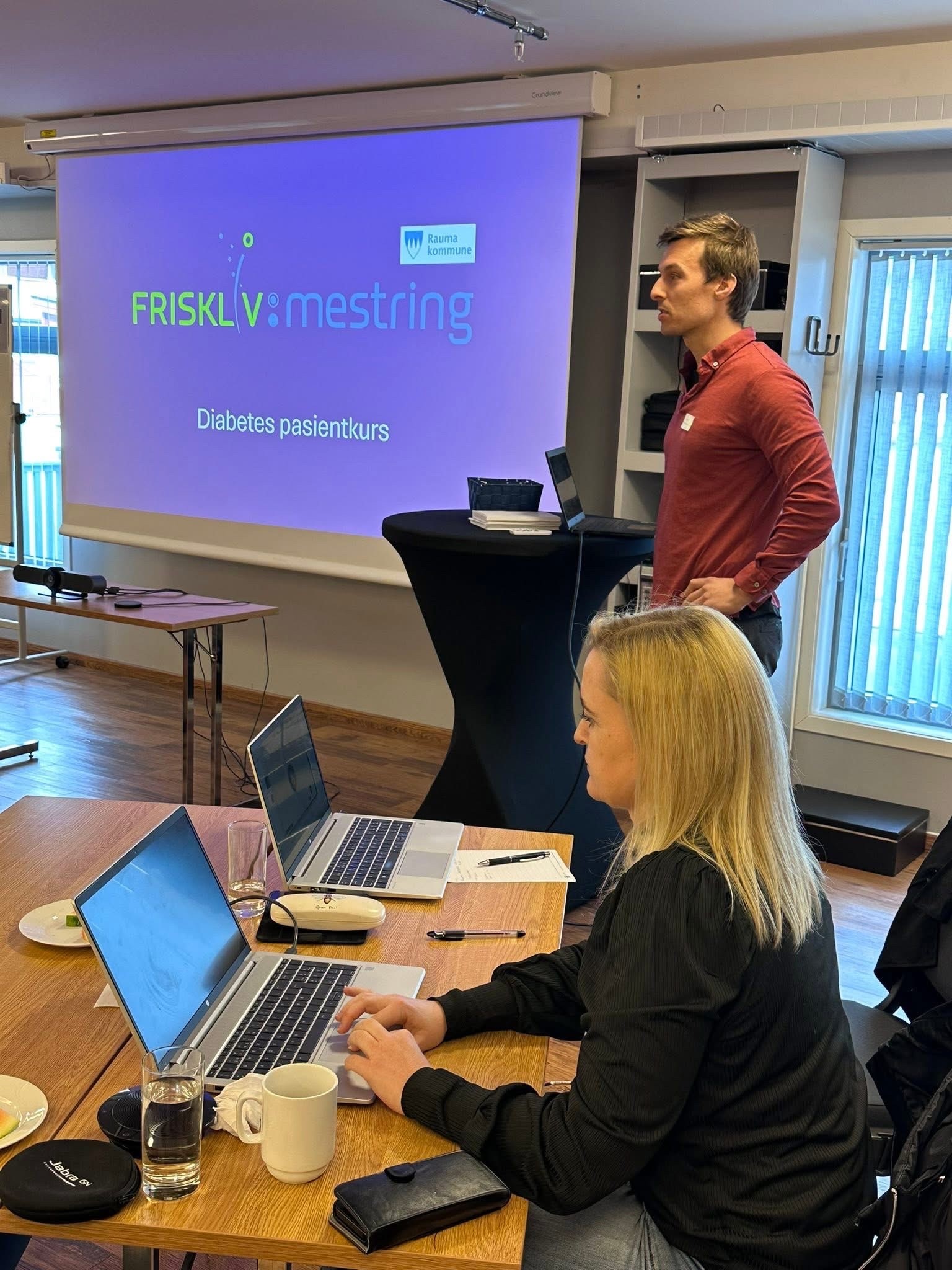 En mann og en kvinne foran en stor skjerm