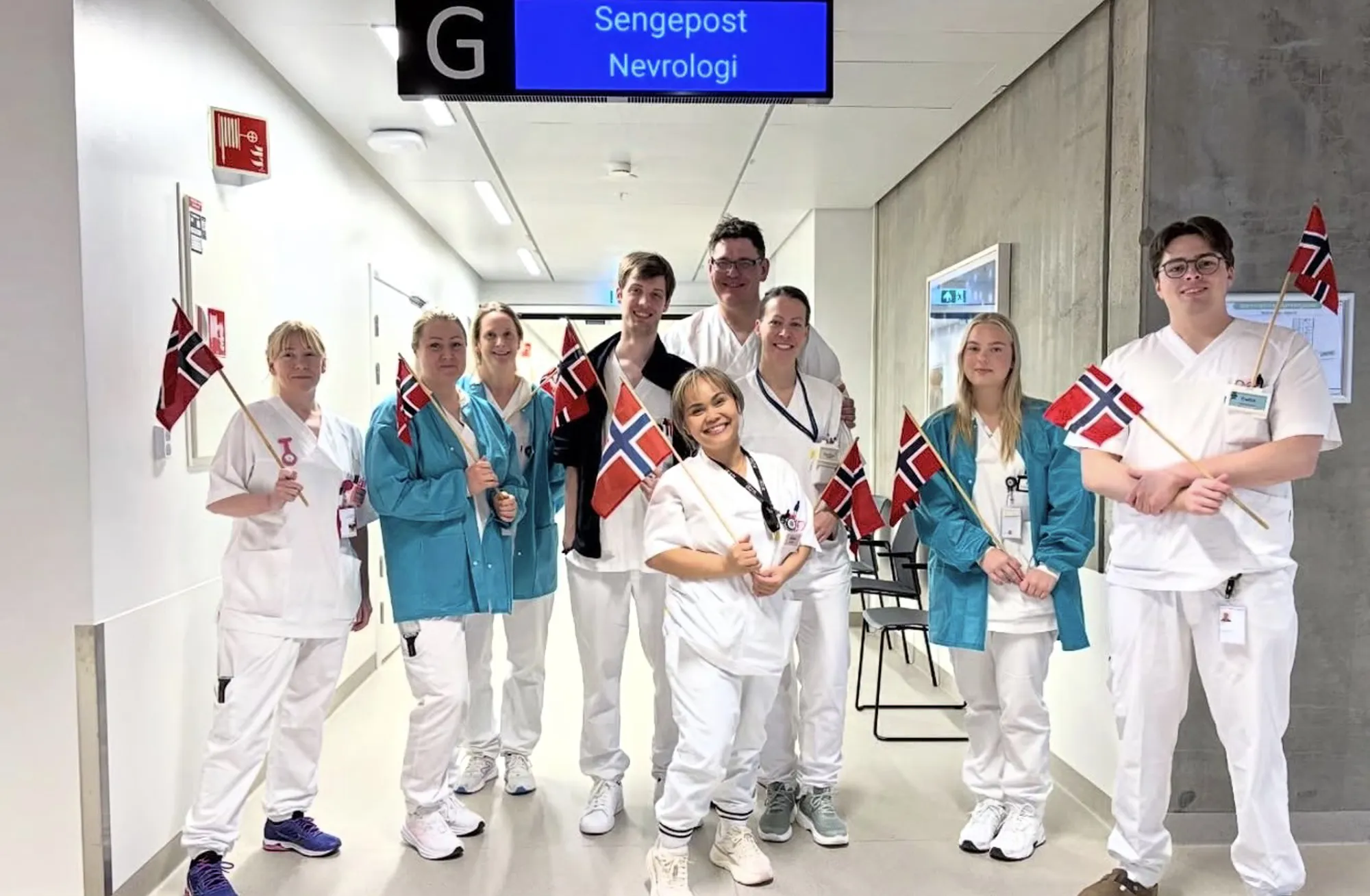 Ni tilsette ved nevrologisk sengepost poserer smilande med flagg for bildet.