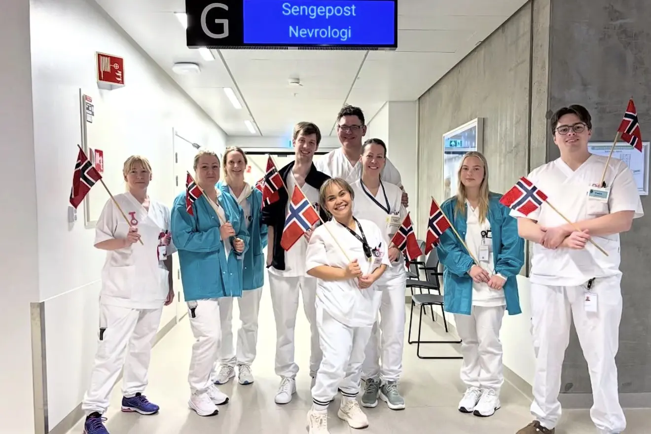 Ni tilsette ved nevrologisk sengepost poserer smilande med flagg for bildet.