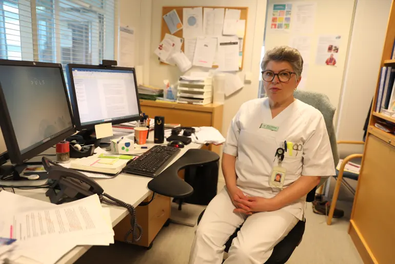 En mann som sitter ved et skrivebord med en datamaskin og andre kontorrekvisita
