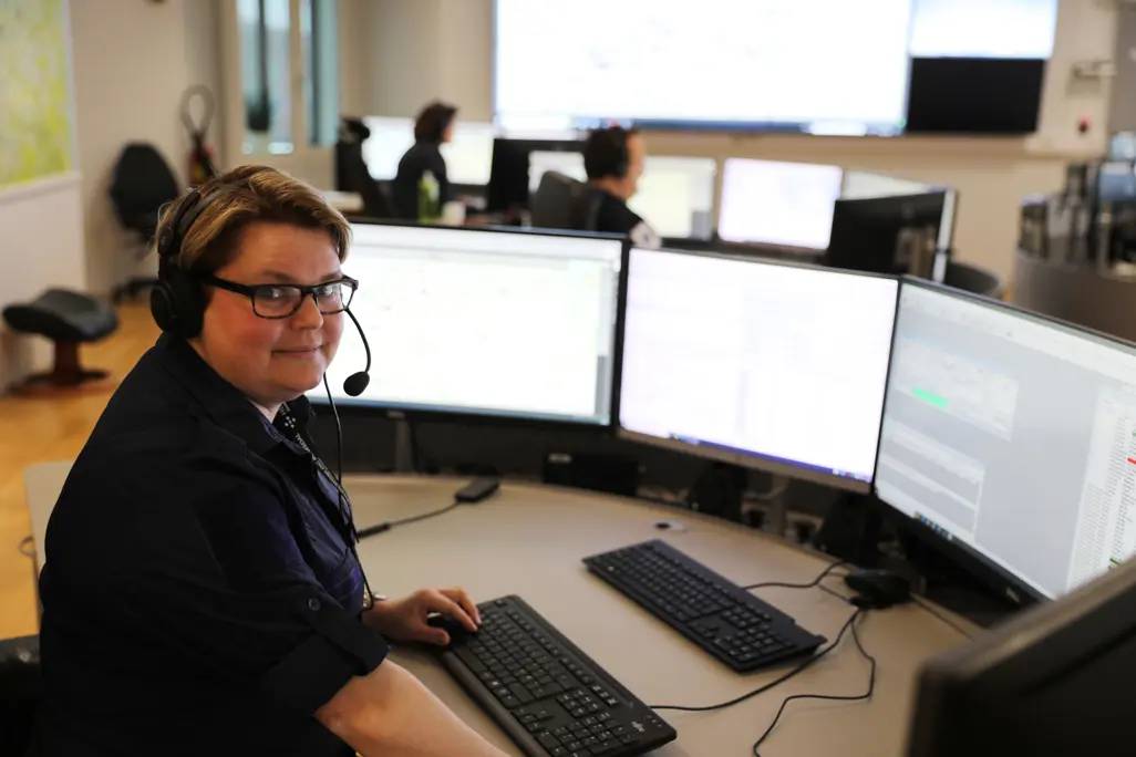 En mann som sitter ved et skrivebord med flere datamaskiner