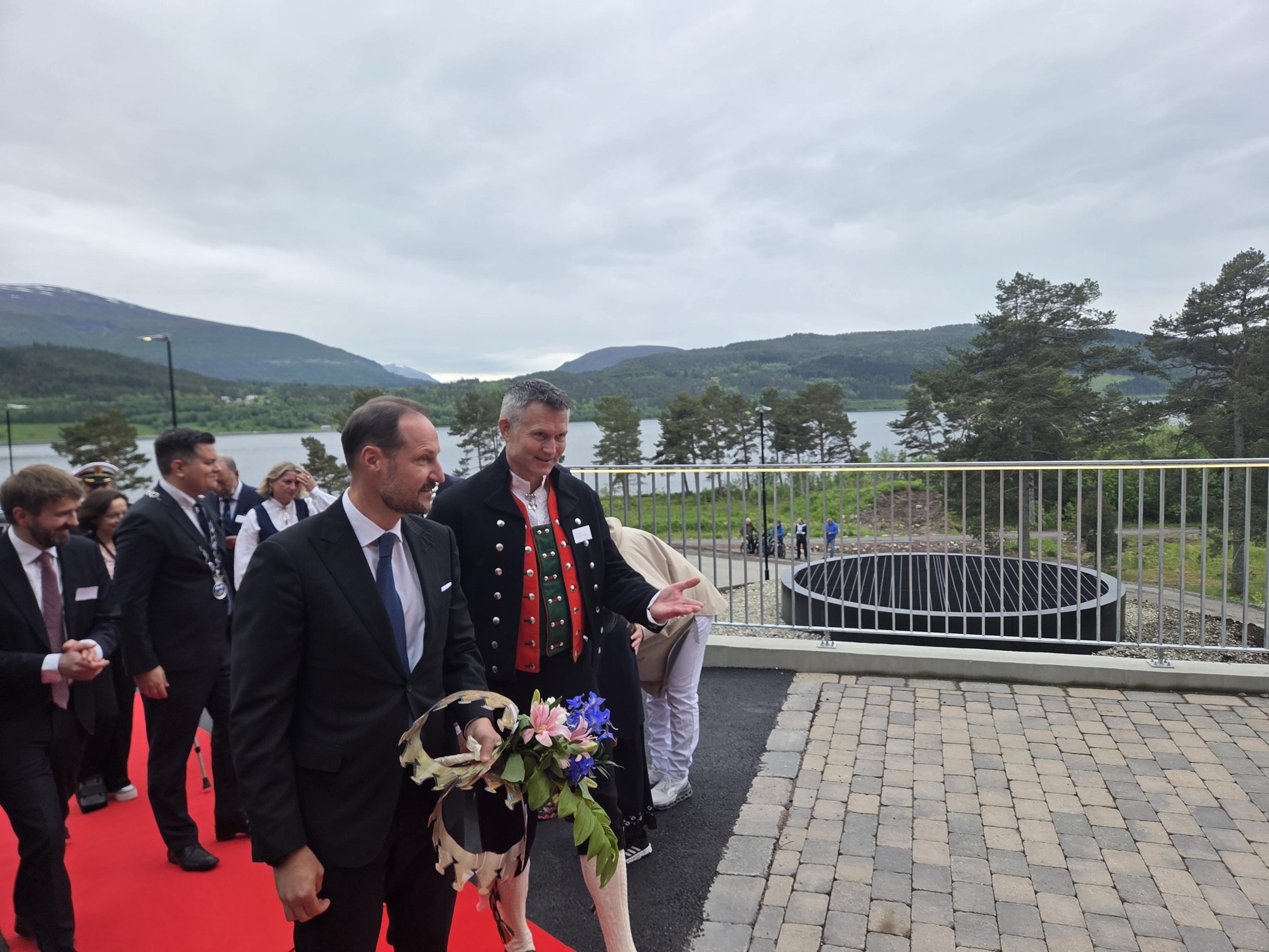 En gruppe menn i dress som holder blomster og går på en steinsti