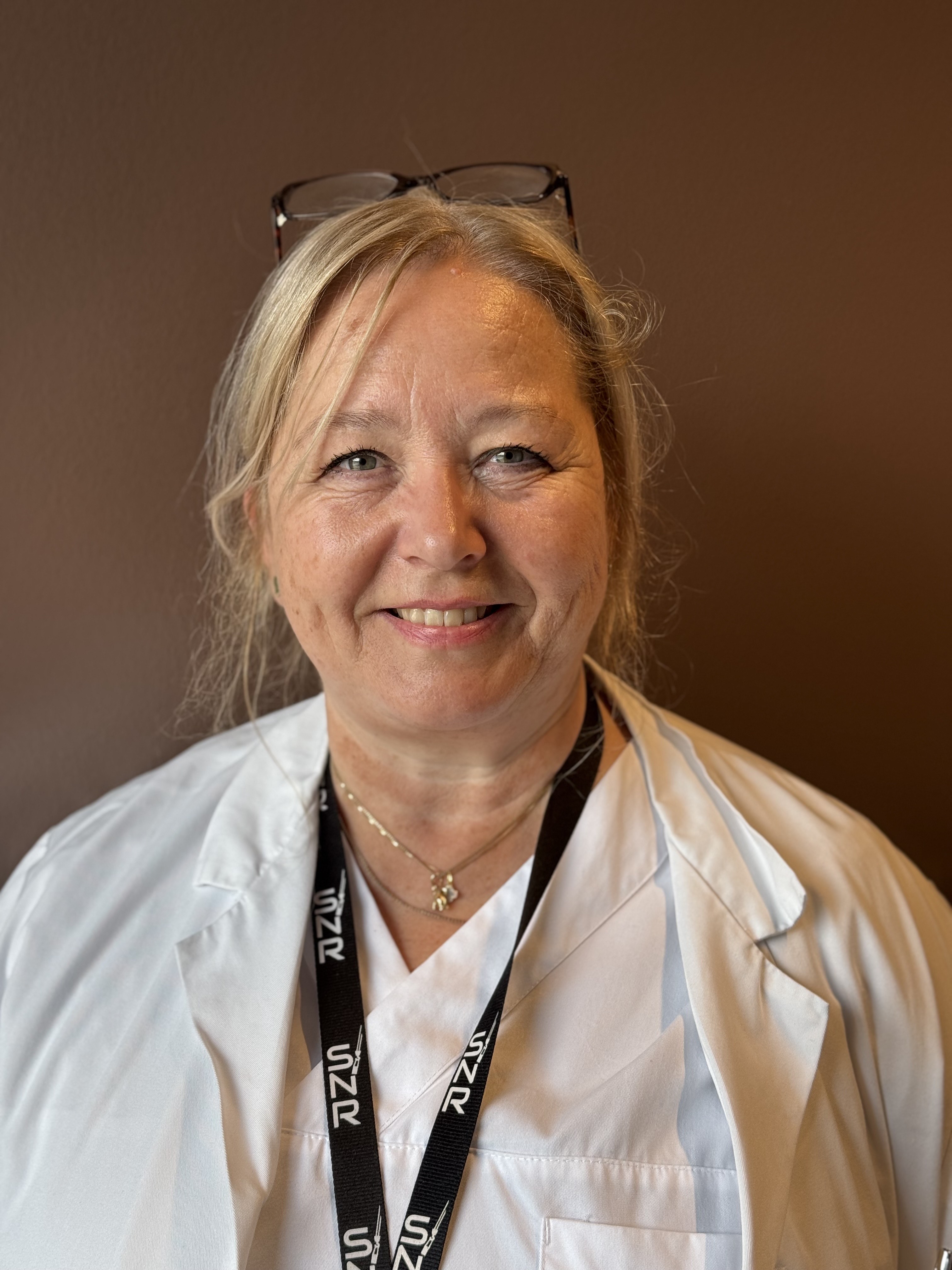 En dame med hvit skjorte og briller på hodet