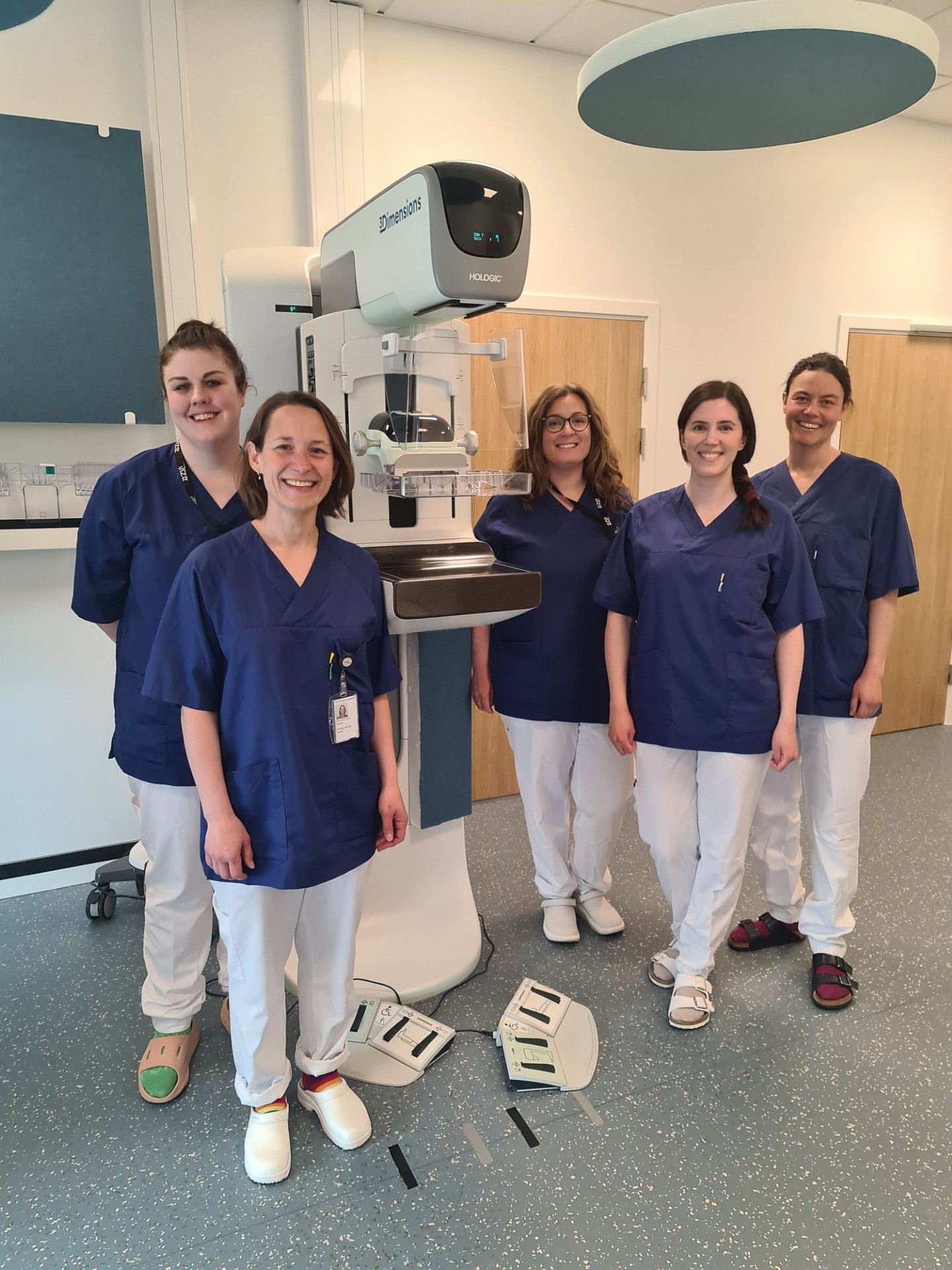 En gruppe ansatte som poserer foran et mammografiapparat.