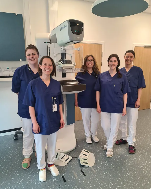 En gruppe ansatte som poserer foran et mammografiapparat.