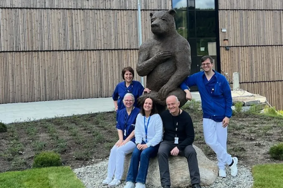 En gruppe mennesker som poserer for et bilde foran en statue