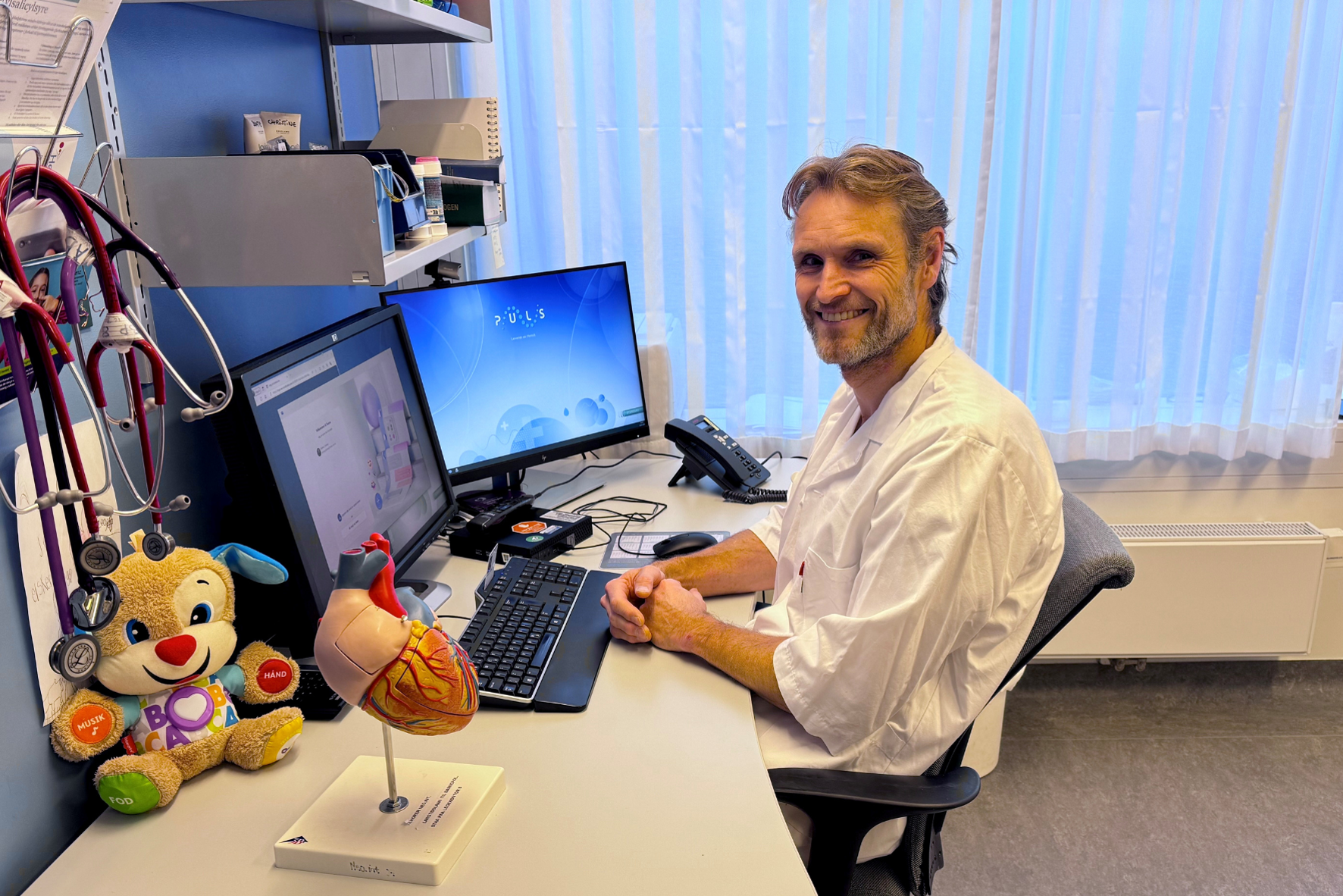 En person som sitter ved et skrivebord med en datamaskin og et kosedyr