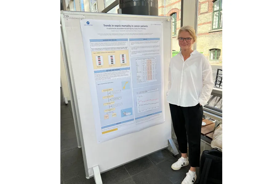 Marit Husby står foran plakat