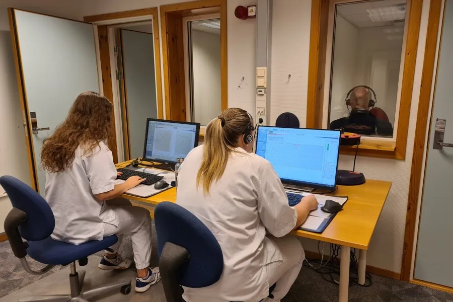 En gruppe mennesker som sitter ved et bord med datamaskiner