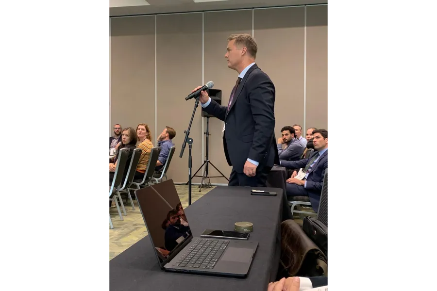 En mann som snakker inn i en mikrofon foran en gruppe mennesker