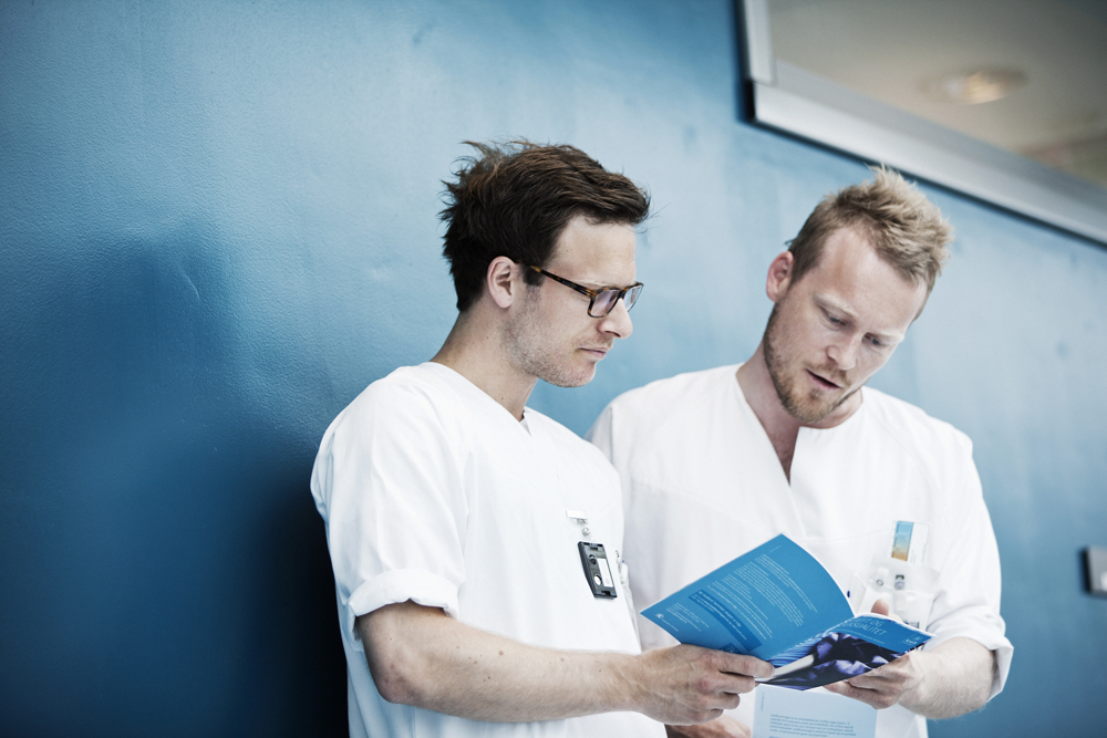 To tilsette i kvitt arbeidstøy som studerer eit dokument i lag.