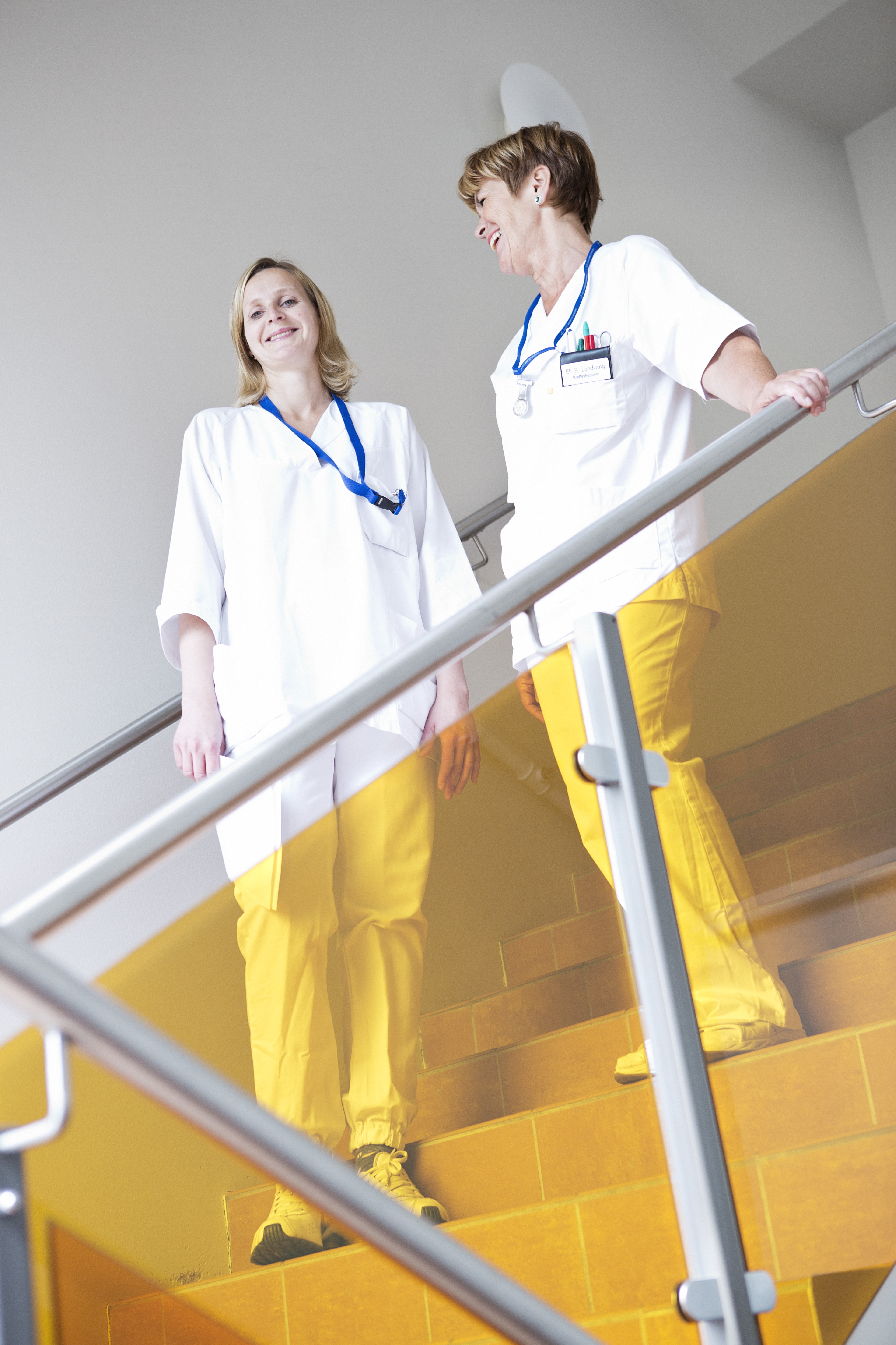 To kvinnelige ansatte poserer for bilde i en trapp på sykehuset.