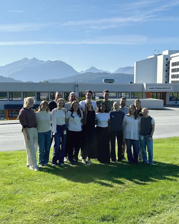 En gruppe mennesker som poserer for et bilde foran en bygning
