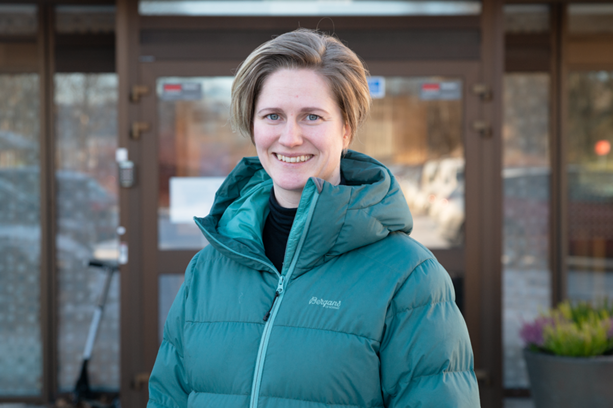 En person som smiler foran en glassdør