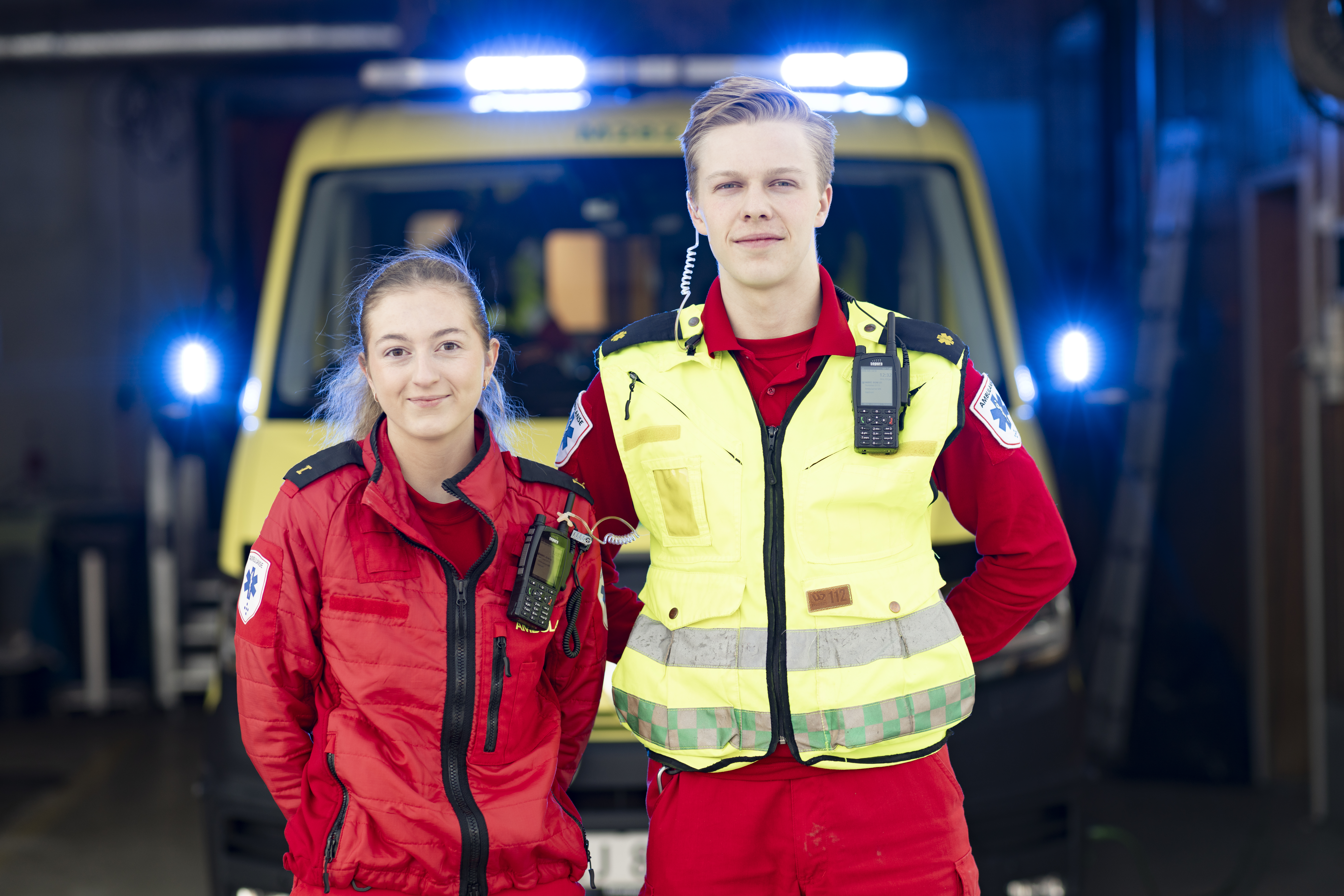 To ambulanseansatte som står foran en ambulansebil