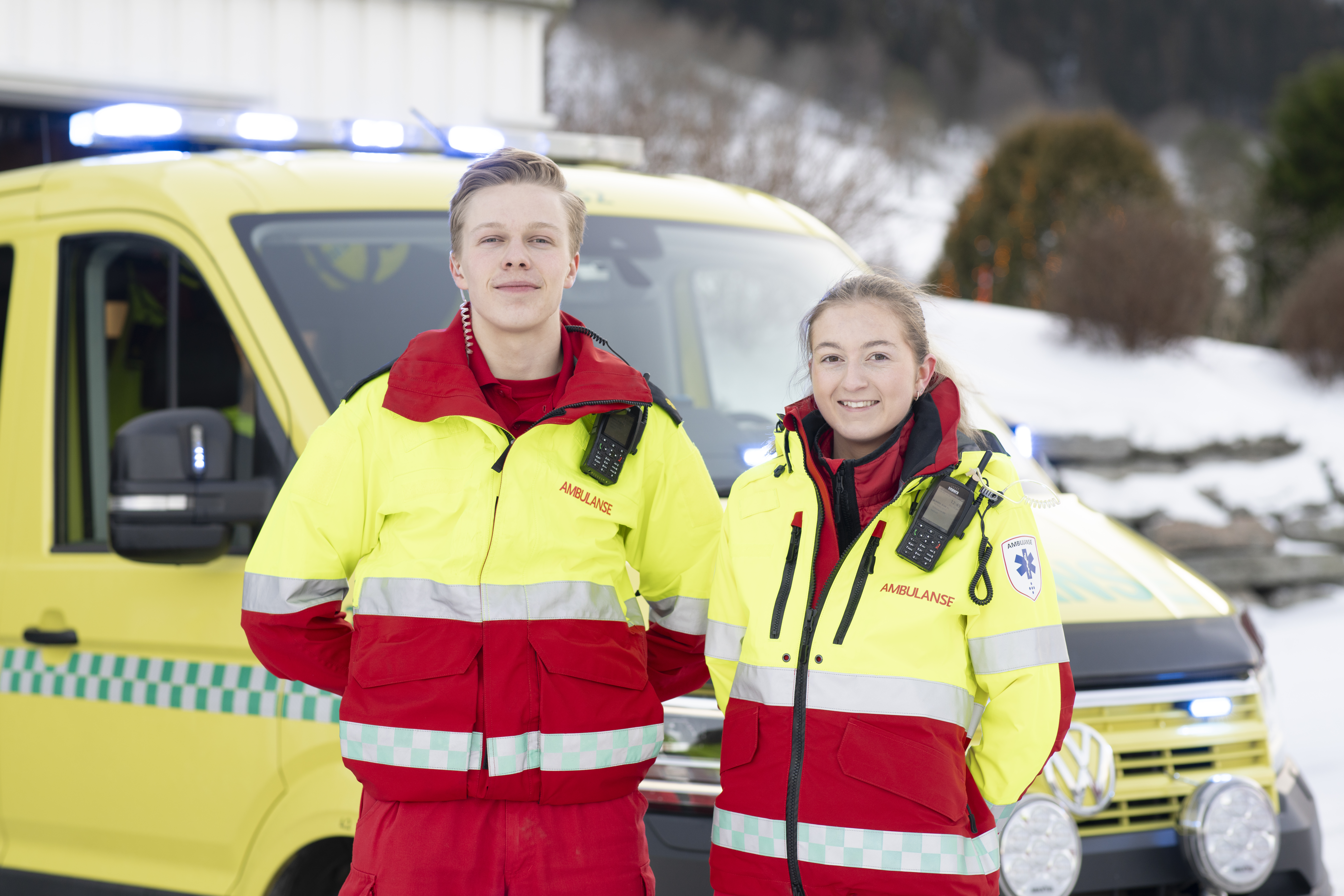 To ambulanseansatte foran en ambulansebil