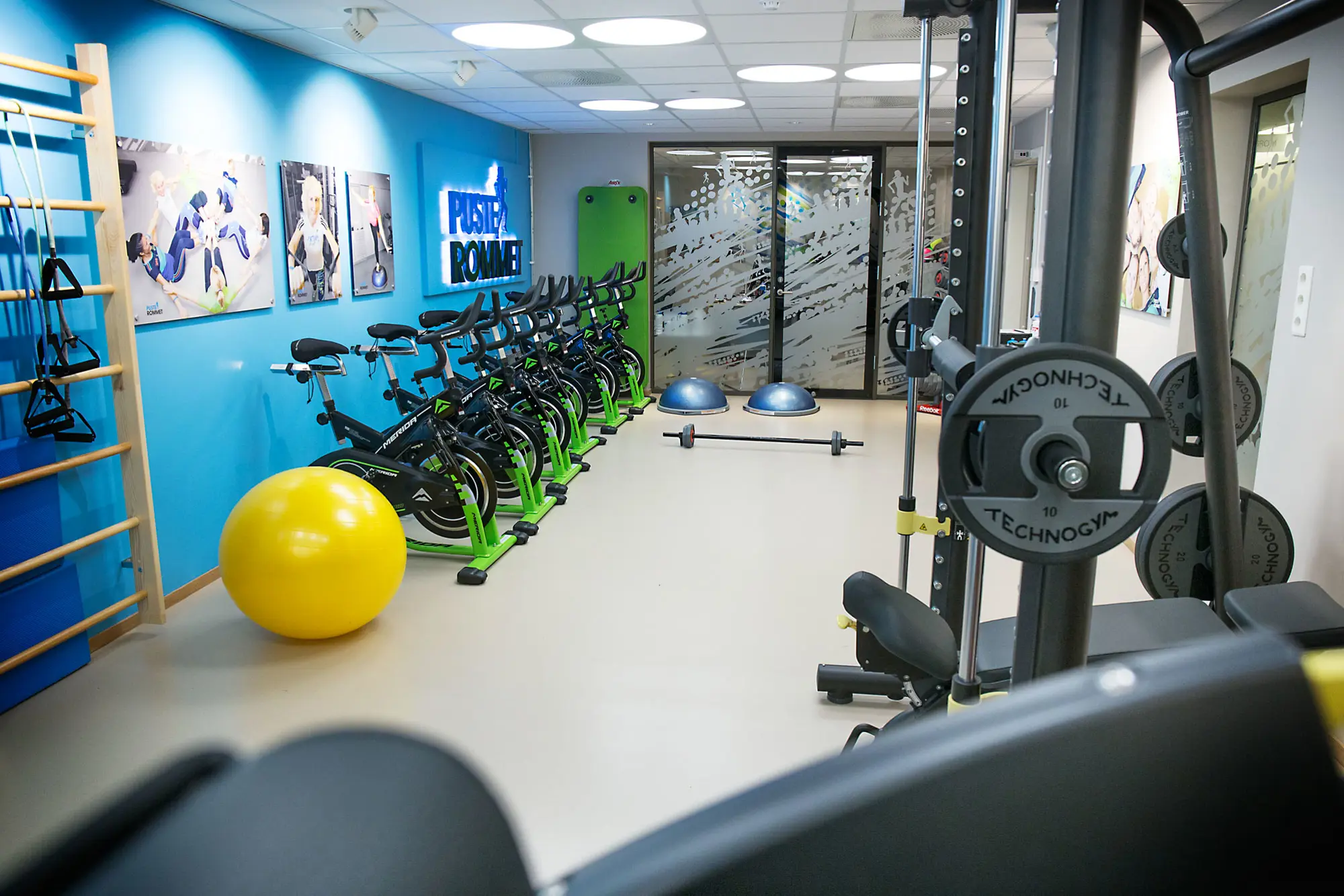 Treningsrom med fitnessball, ribbevegg, spinningsyklar og vekter.