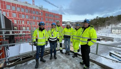 En gruppe mennesker i gule jakker som står i snøen