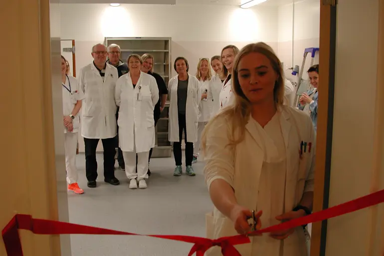 En gruppe mennesker i hvite labfrakker står i gangen