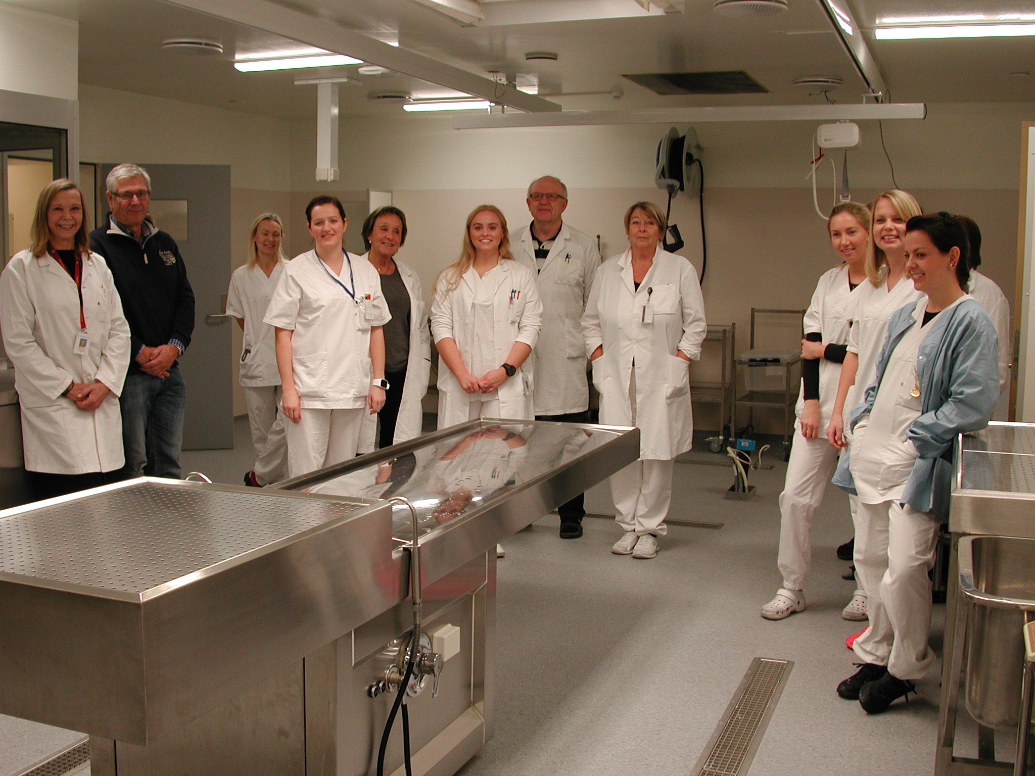 En gruppe mennesker i hvite labfrakker som står i et rom