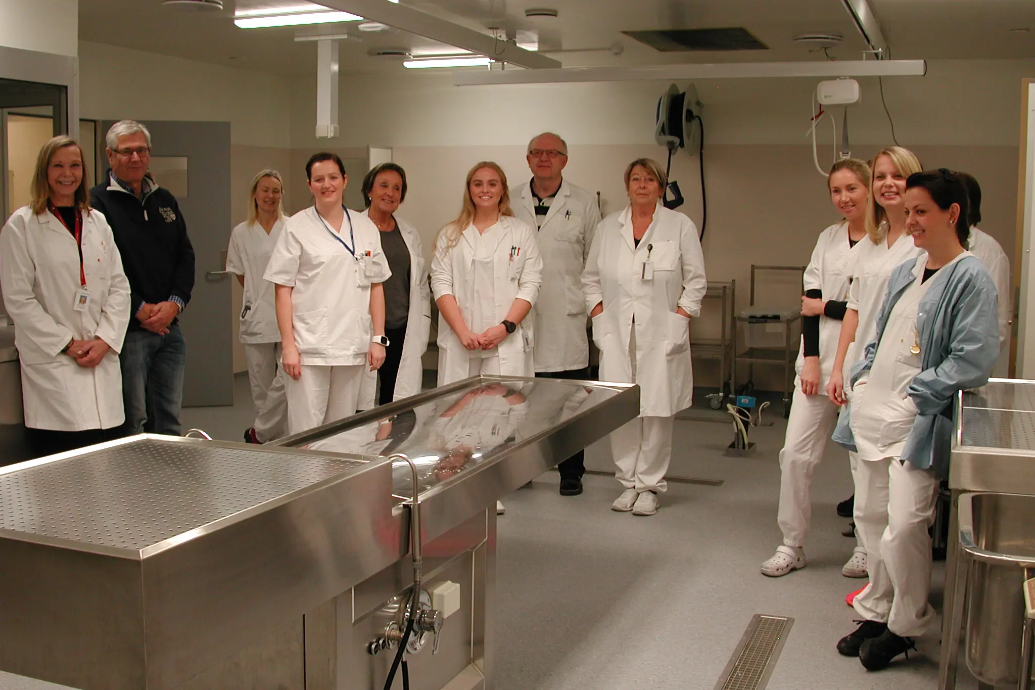 En gruppe mennesker i hvite labfrakker som står i et rom