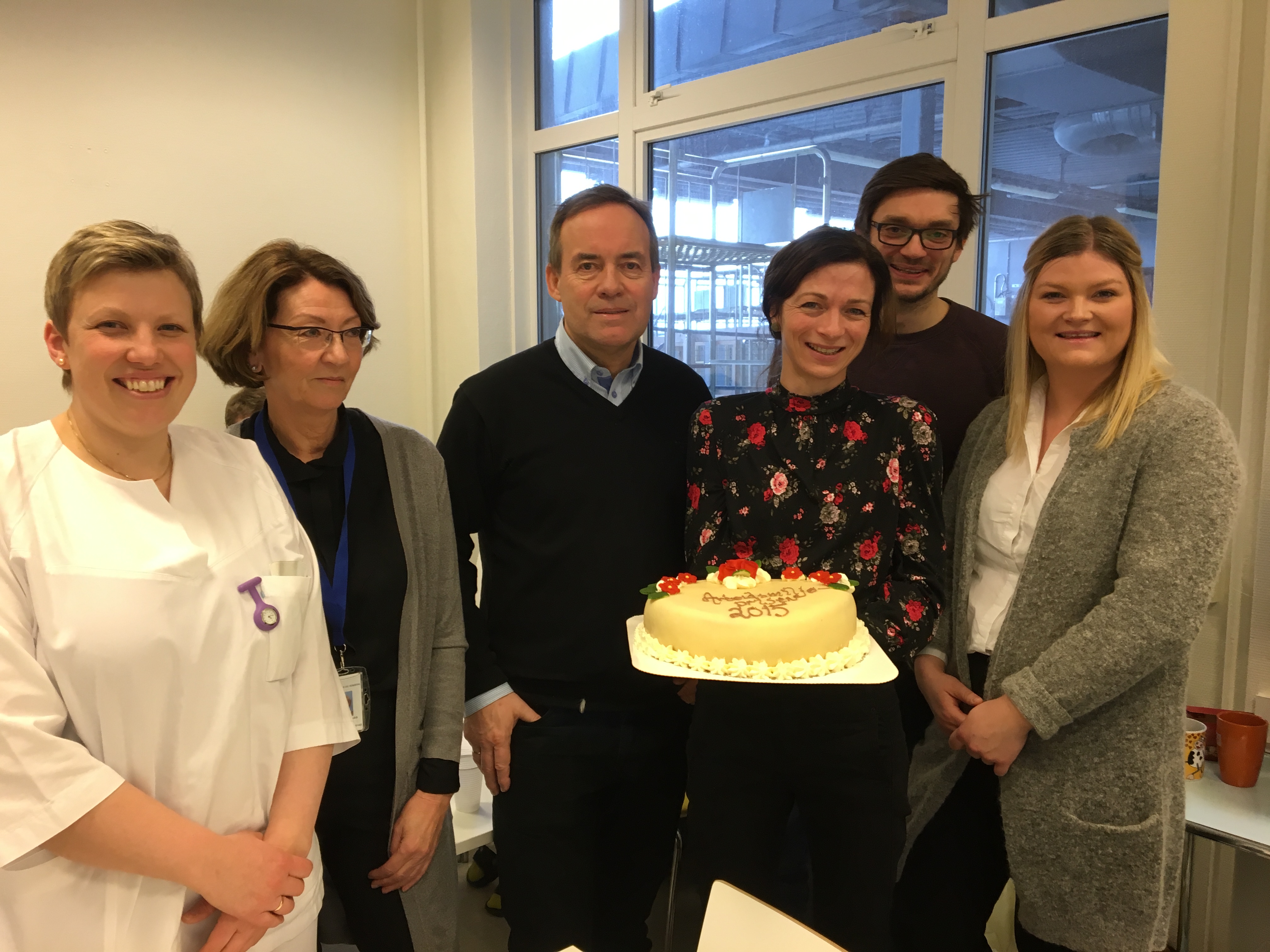 En gruppe mennesker som poserer for et bilde med en kake