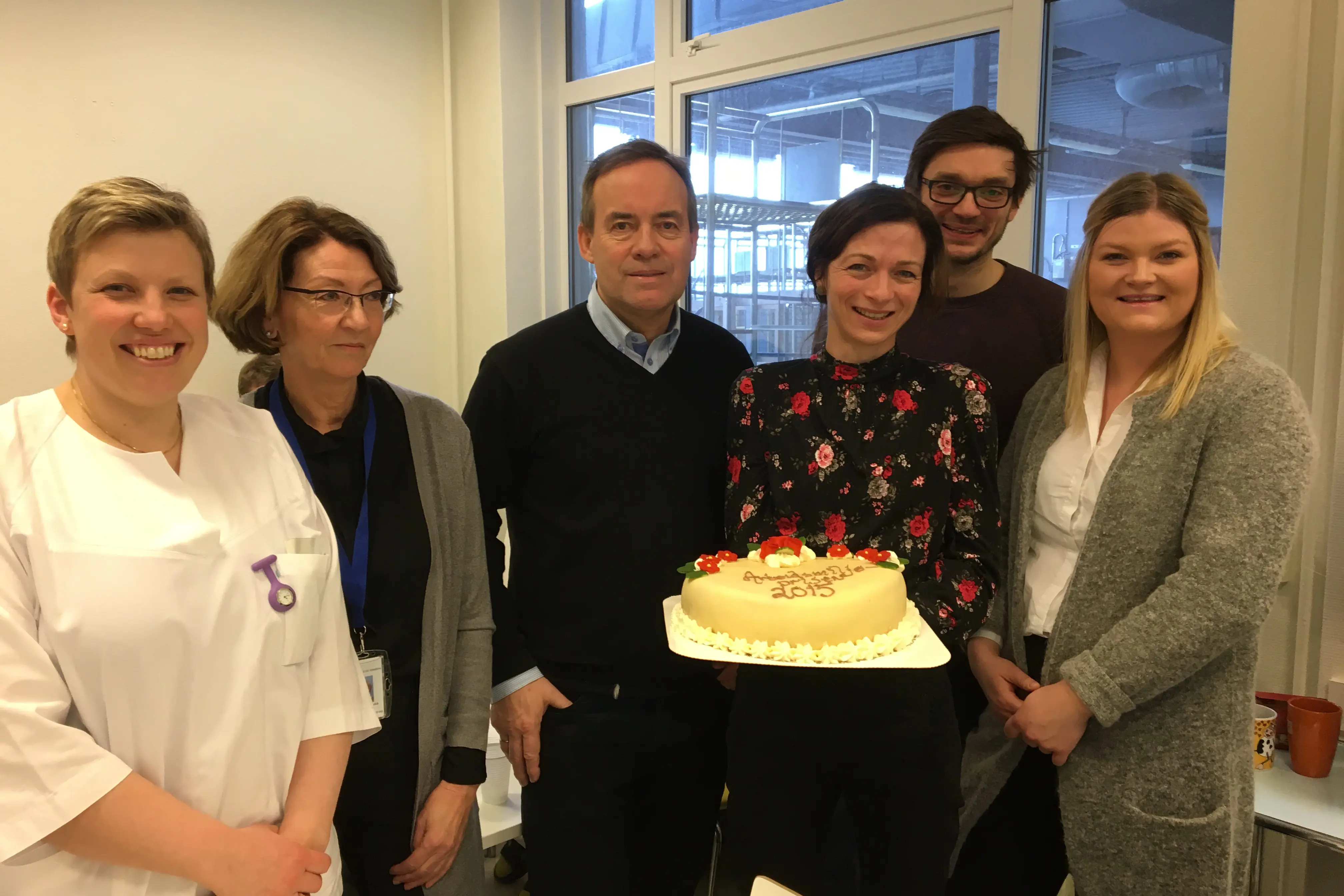 En gruppe mennesker som poserer for et bilde med en kake