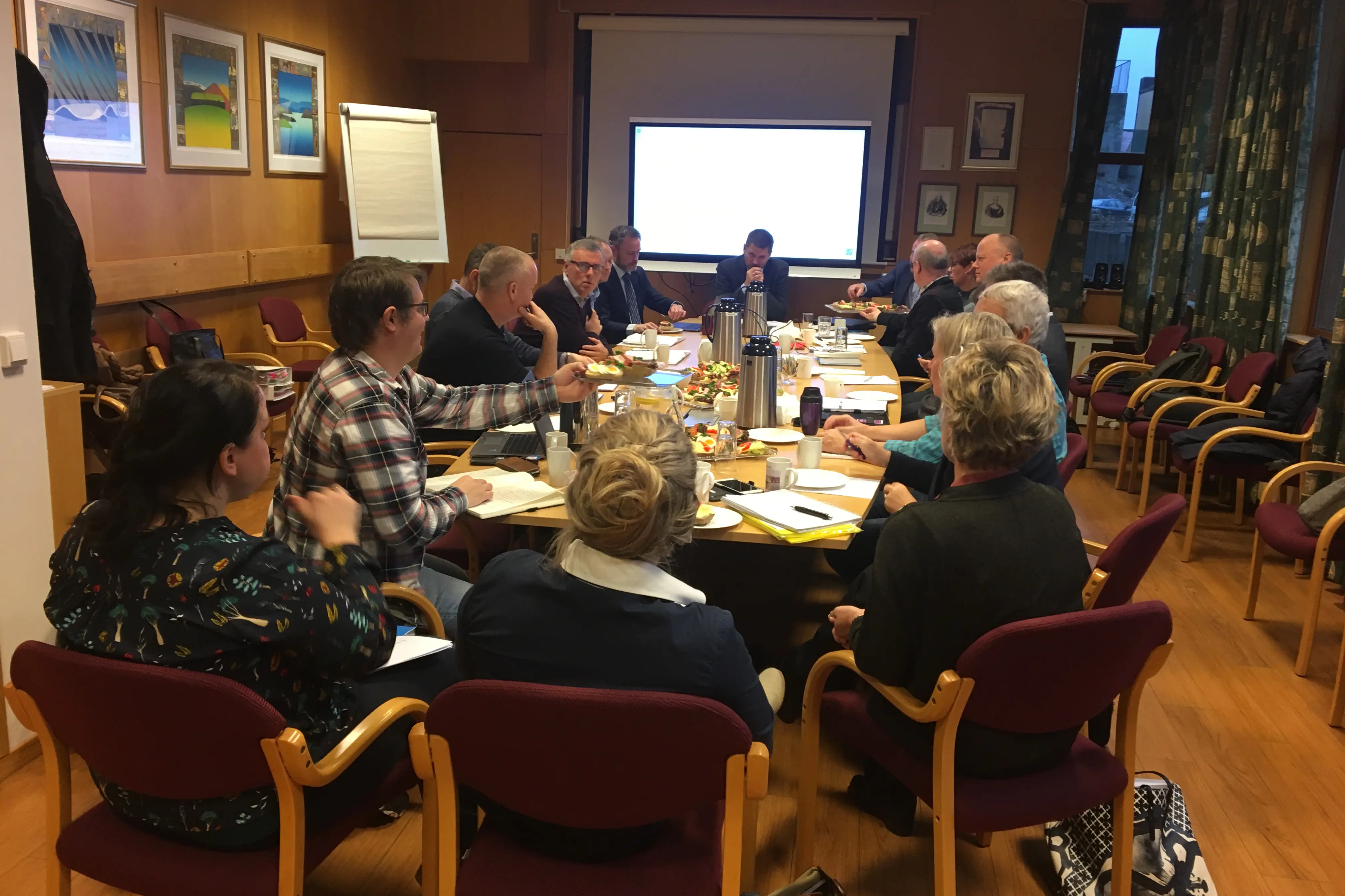 En gruppe mennesker som sitter rundt et bord og ser på en presentasjon