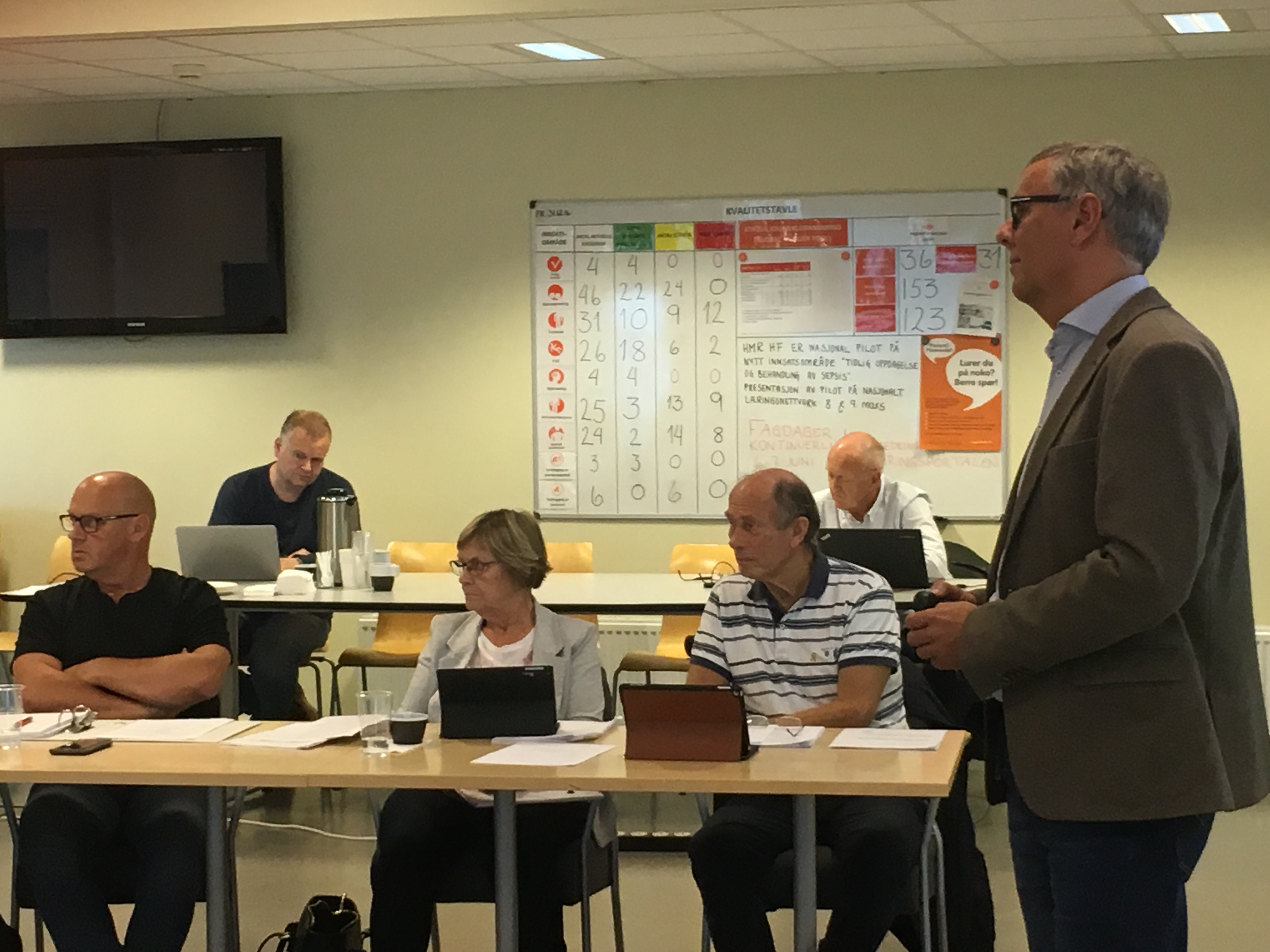 En mann som står foran en gruppe mennesker som sitter ved bord