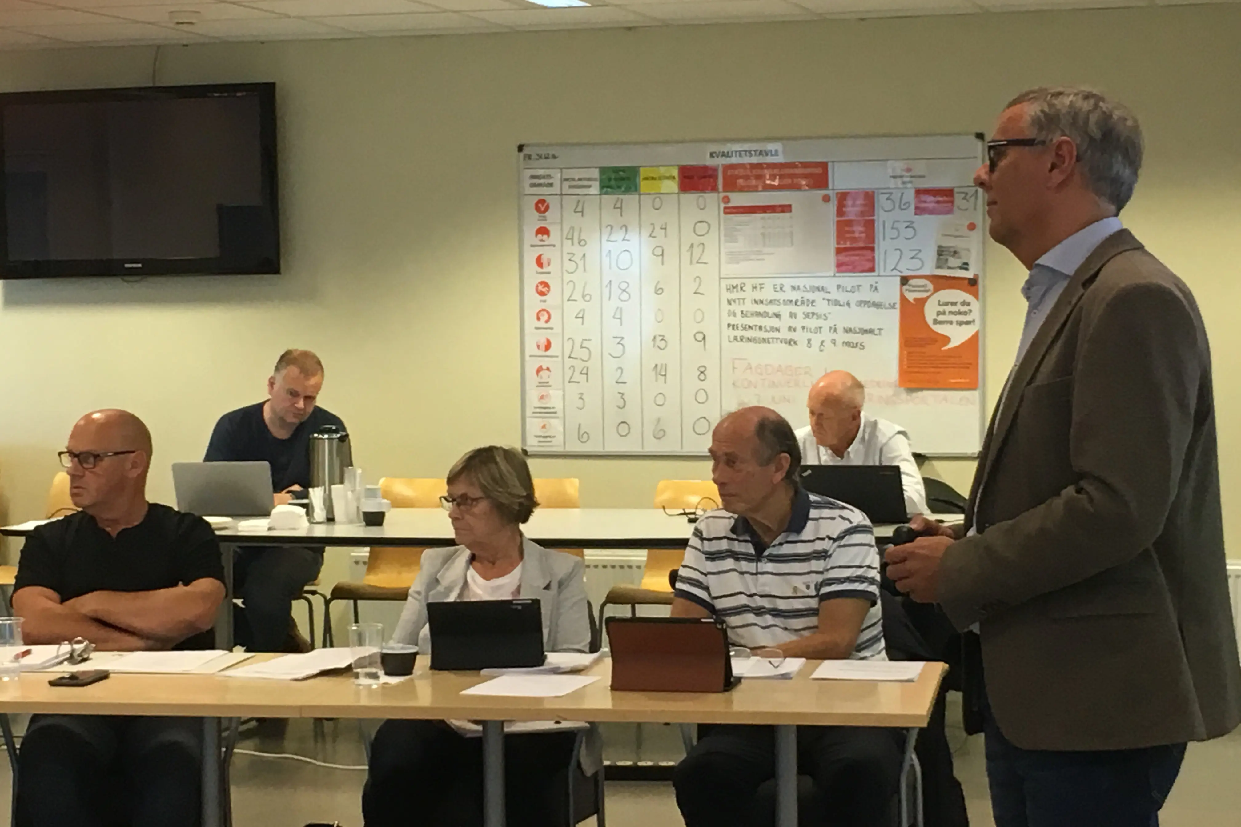 En mann som står foran en gruppe mennesker som sitter ved bord