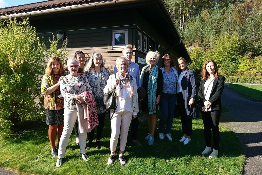 En gruppe mennesker som poserer for et bilde foran et hus