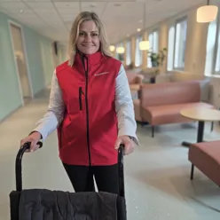 En person med rød vest som holder i en rullestol.