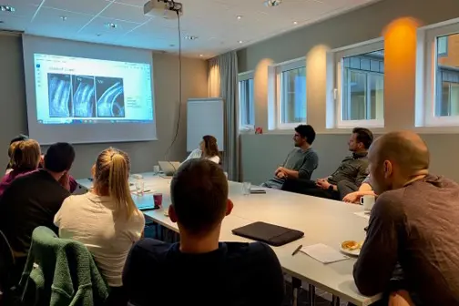 En gruppe mennesker som sitter rundt et bord og ser på en presentasjon