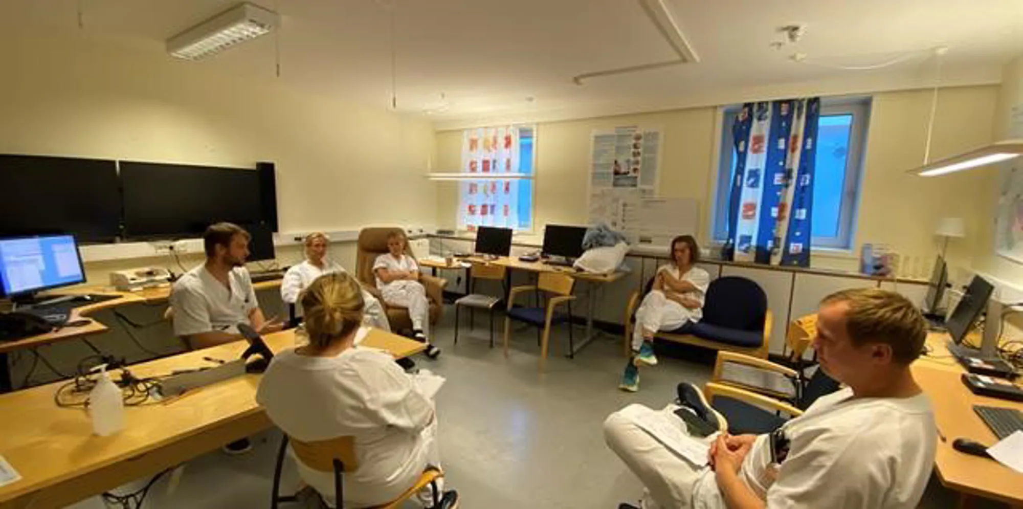 En gruppe mennesker som sitter i et rom med datamaskiner