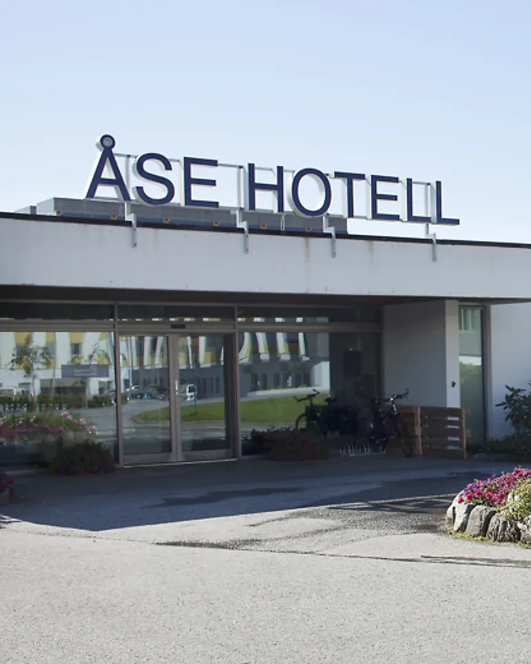 Inngangsparti med store bokstaver "ÅSE HOTELL" på taket.