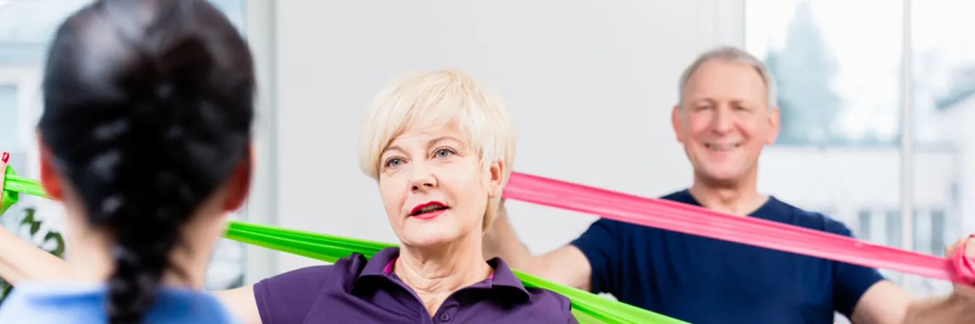 Kvinne og mann som trener med strikk i lag med fysioteapeut