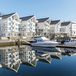 Et par båter i en vannmasse ved en rekke bygninger