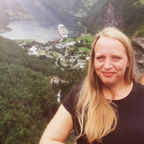 En kvinne som smiler med en by i bakgrunnen